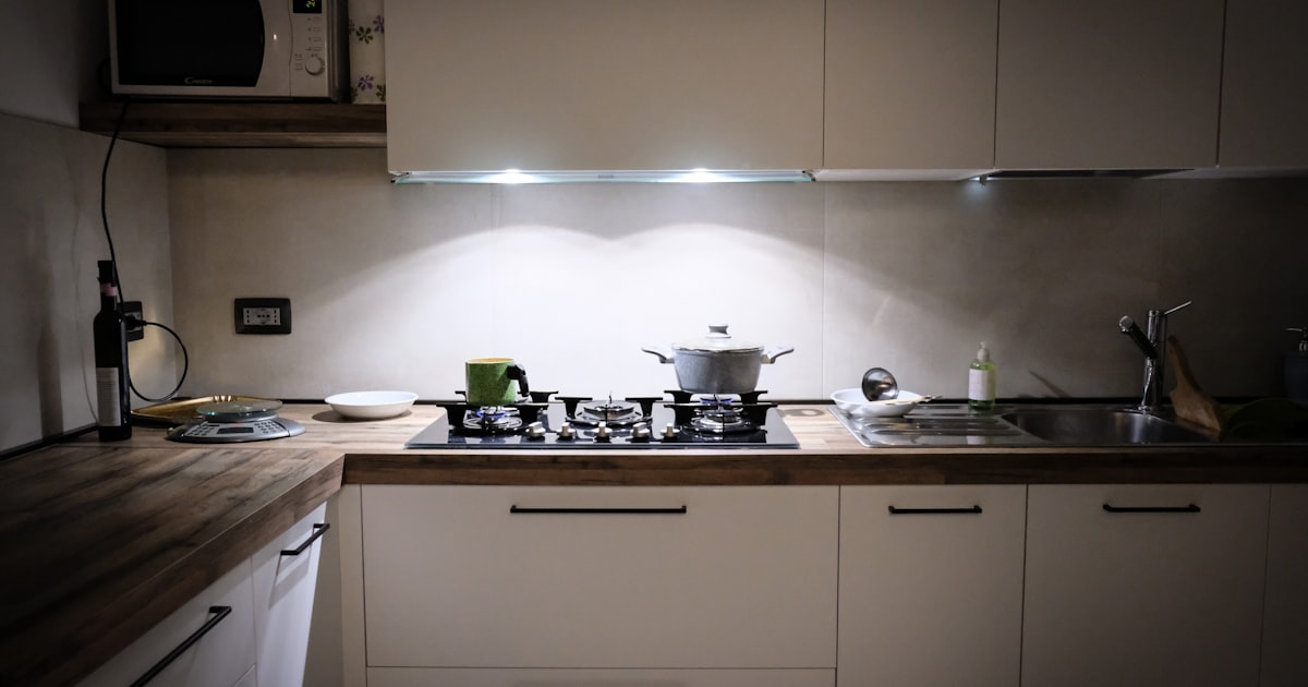 White wooden cabinetry with a stainless steel sink in an organized minimalist kitchen