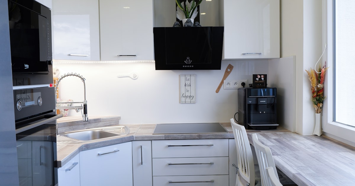 Modern white kitchen featuring built-in appliances and an island seating arrangement