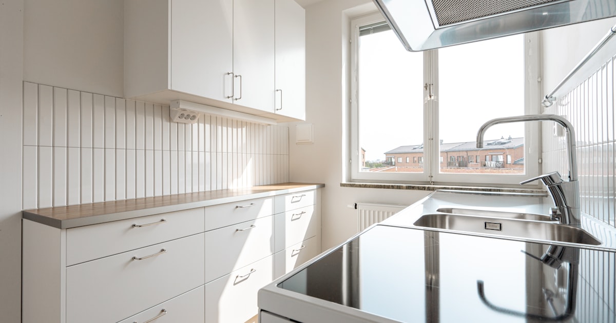 Compact small white kitchen with stovetop near a window